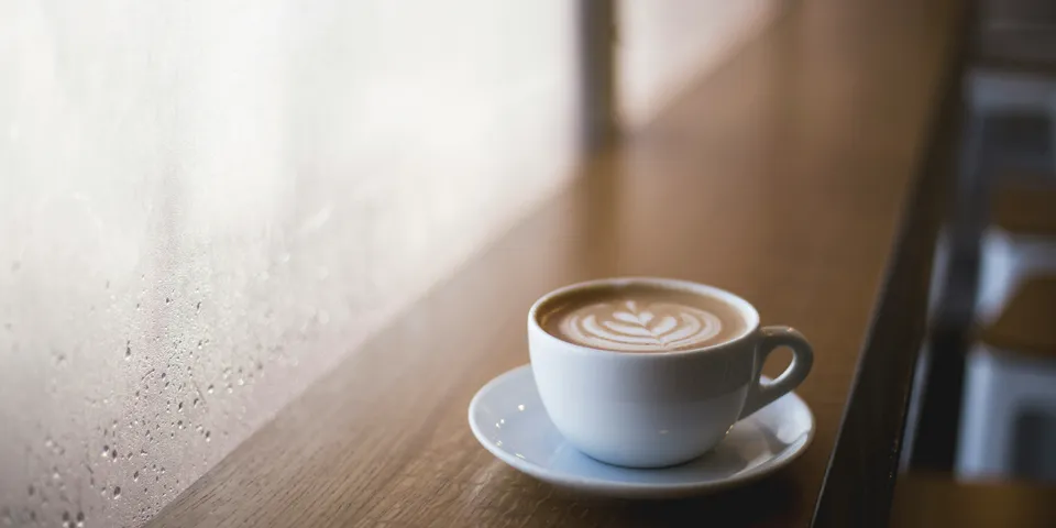 A cup of coffee on a cafe counter by the window.