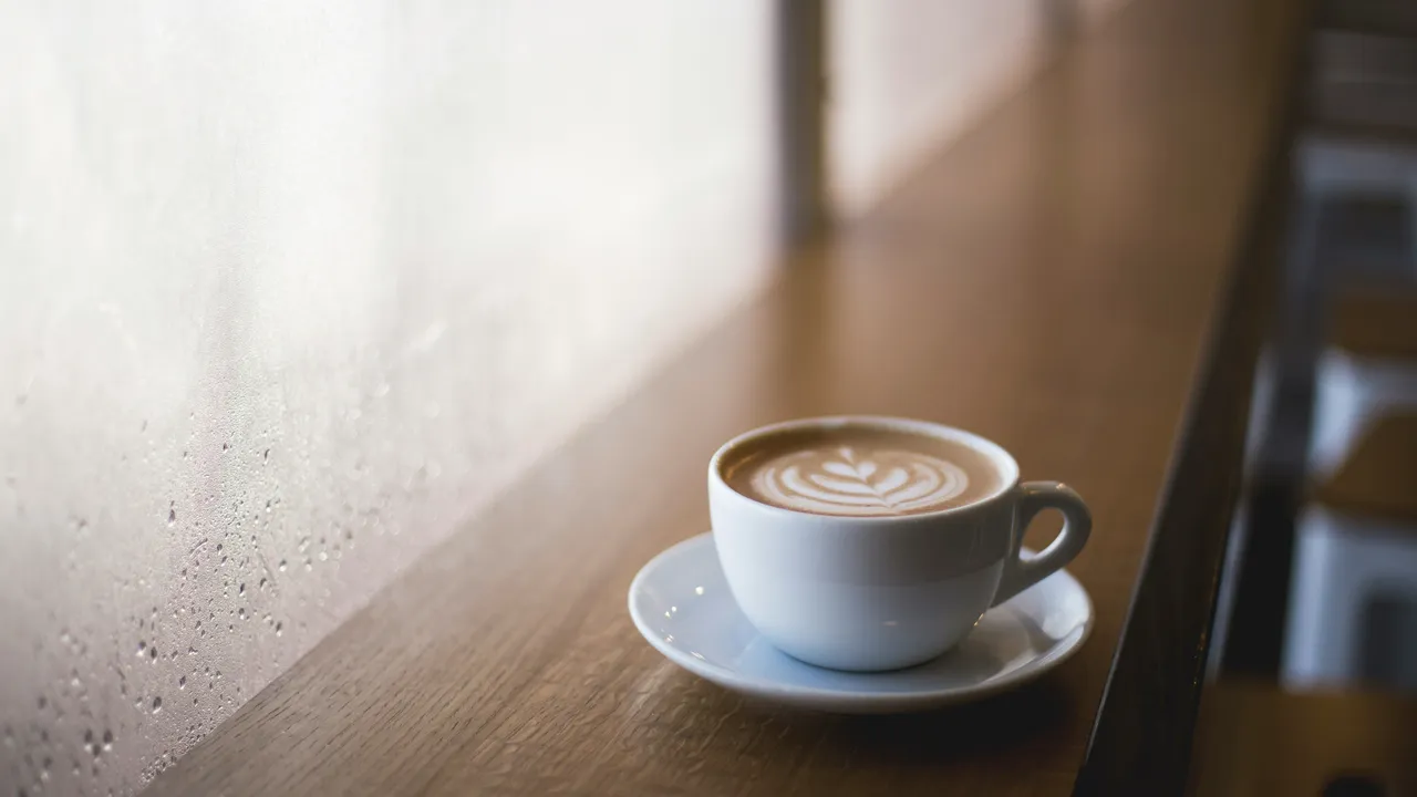 A cup of coffee on a cafe counter by the window.